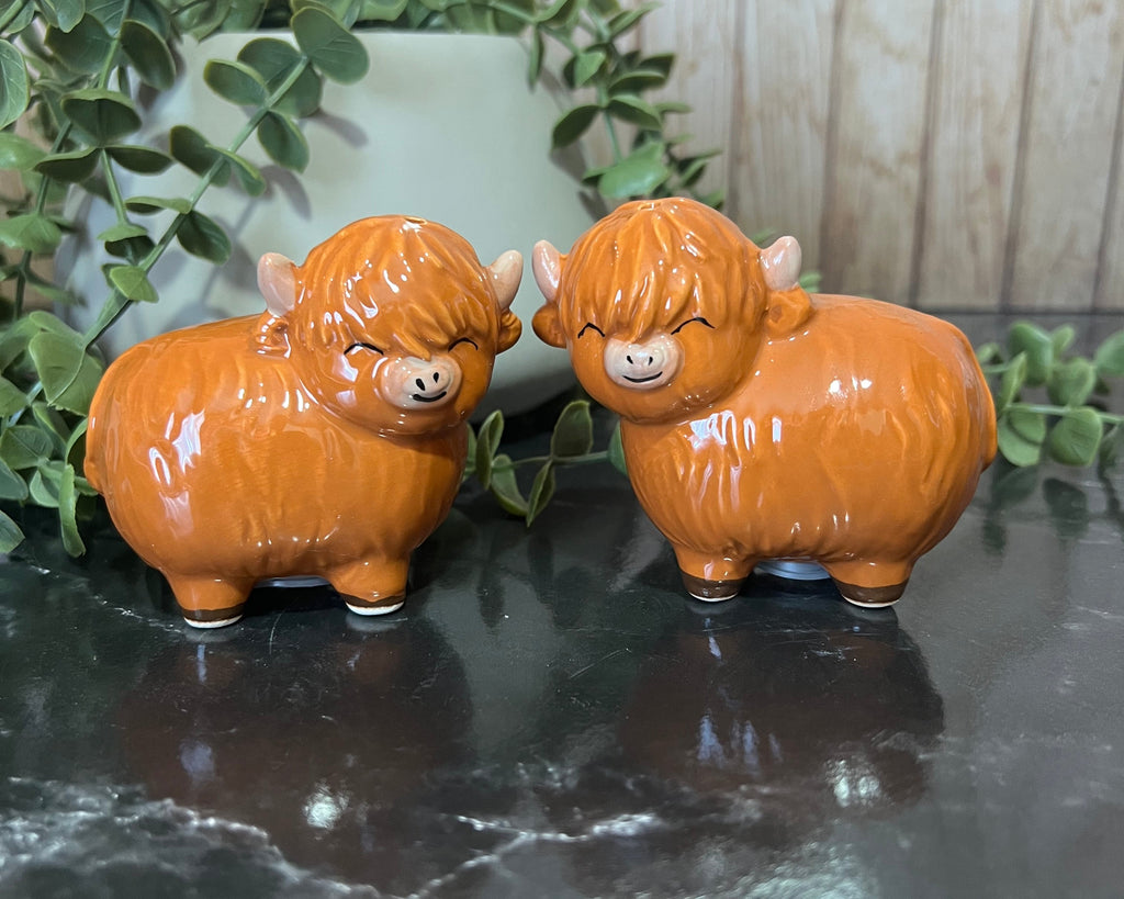 Highland cow salt and pepper shakers in orange ceramic, featuring charming smiling expressions.